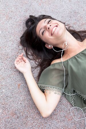 Portrait of young girl listening to music lying on the floor of urban graniteの写真素材