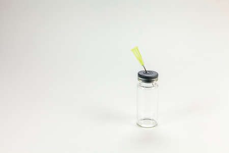 Glass vaccine bottle held by a hand with surgical gloves