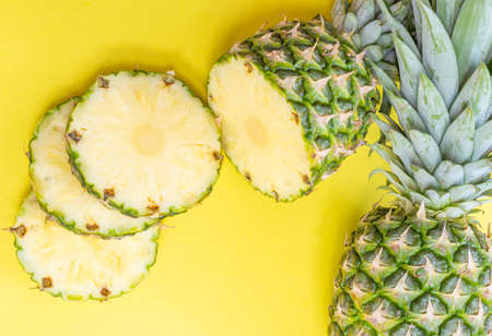 chopped fresh ripe pineapple fruits on a yellow background close-upの写真素材