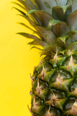 juicy and fresh whole pineapple with leaves on a yellow background