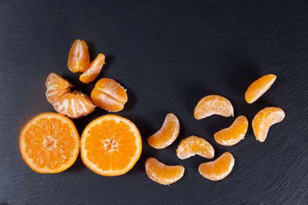 Tangerines on a black stone background. Tangerine slices.の写真素材