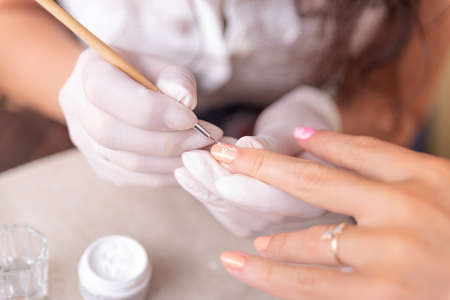 Close-up of a female manicurist applying nail polish with a brush.の写真素材