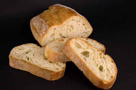 A loaf of bread with slices stacked in front