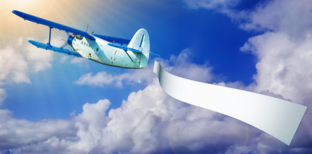 airplane with a banner against a blue skyの写真素材