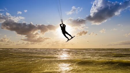Silhouette of a kitesurfer against a sunsetの写真素材