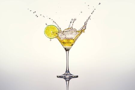 Cocktail glass with lime and splashesの写真素材