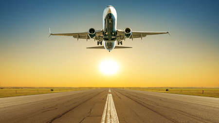 commercial airplane takes off against a sunsetの写真素材