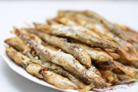 Fried smelt in a frying pan on the table with spices, lime and thyme. Small crispy fish. Selective focusの写真素材