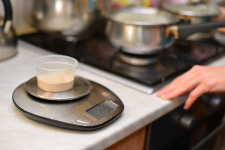 Woman pouring sugar into a kitchen scale.の写真素材