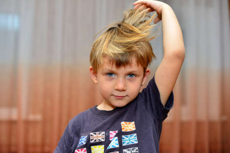 Portrait of young amazed boy. Happy young boy with blond hair wearing a blue-striped t-shirt. Serious look. Outdoor shotの写真素材