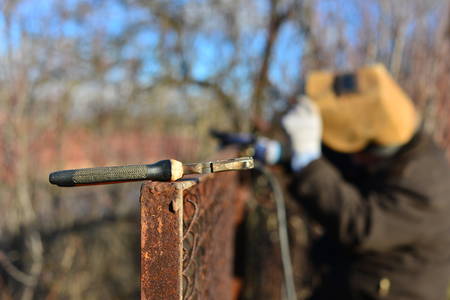 welder makes a fence in the street. Electric welder makes the fence in his own manorの写真素材