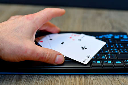 Online gambling concept with a businessman seated at his desk holding a tablet computer showing a...