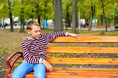 The young boy sits on a bench in parkの写真素材