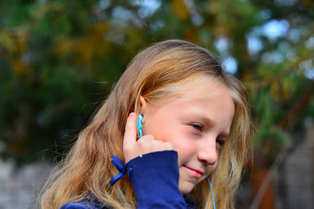girl in headphones with phone in the forest with her hair downの写真素材