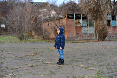 boy playing and jumping with stick in hand. Little boy playing in puddle in spring forest. happy childhoodの写真素材