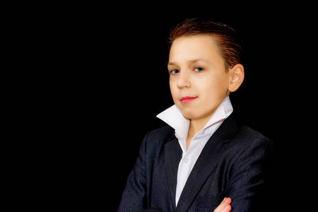 Portrait of handsome teenager in navy blue suit and white shirt. Elegant boy in business suit isolated on black background.の写真素材