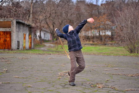 boy playing and jumping with stick in hand. Little boy playing in puddle in spring forest. happy childhoodの写真素材
