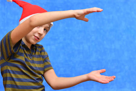 Cute little boy in Santa hat on color background