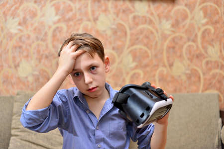 Happy teen boy wearing virtual reality goggles watching movies or playing video games. Cheerful...