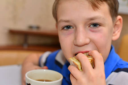 Young boy drinking some coffee from a mug and making eye contactの写真素材