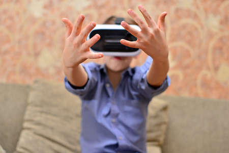 Happy teen boy wearing virtual reality goggles watching movies or playing video games. Cheerful...