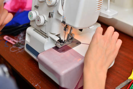 Portrait of a beautiful seamstress carrying a tape measure and working in a textile factory