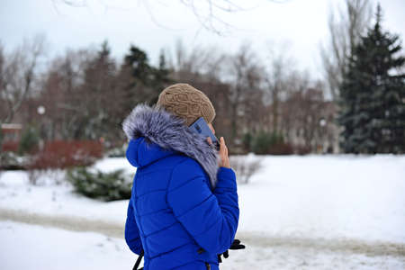 Girl in a blue jacket talking on the phone in the street in the winterの写真素材