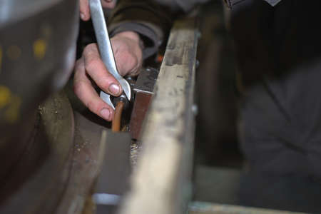 metalworking industry: factory man worker in uniform working on lathe machine in workshopの写真素材