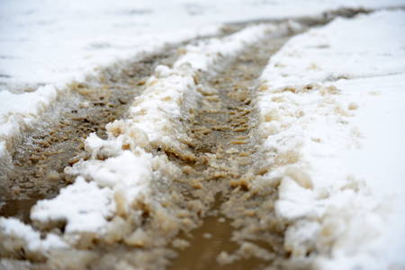 The snow melts on the road and turns into a puddle and slush in the cityの写真素材