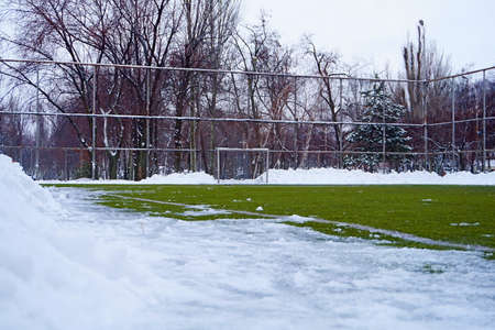 Football field in snow in the winter. A white marking on a green field and white gate for game in football.の写真素材