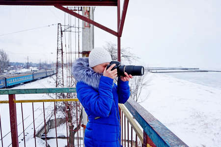 The girl photographs in the winter in dark blue clothes
