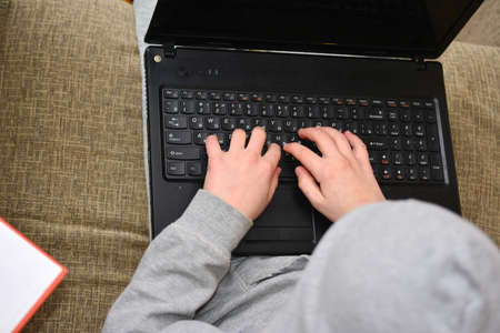 The guy with the laptop sits on the couch and prints with the keysの写真素材