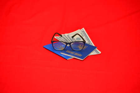 Two Ukrainian passports with glasses and dollars on an isolated red background. The concept of traveling alone, in love.の写真素材