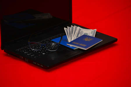 Two Ukrainian passports with dollar money are on the laptop. The concept of traveling alone, in love.の写真素材