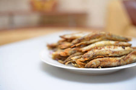 Fried smelt in a frying pan on the table with spices, lime and thyme. Small crispy fish. Selective focusの写真素材