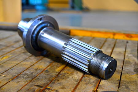 The new splined shaft after machining on the lathe and CNC milling machine lies on a wooden rack in...