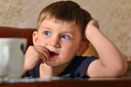 A boy eats fried seeds at home in the kitchen at a table close-up of a seed