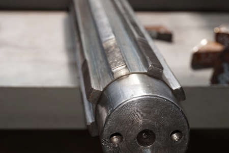 Splined shaft after disassembly of teeth lies on the rack in the workshop in production