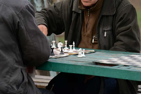 Active people in their free time on vacation with pleasure playing chess on the street. Figures and chess board close-up.の写真素材