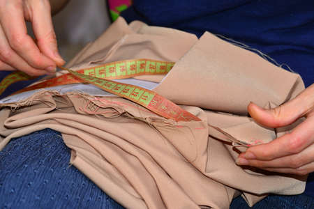 A woman sews a piece of cloth. Produces a measurement of a centimeter for the pattern of clothing.