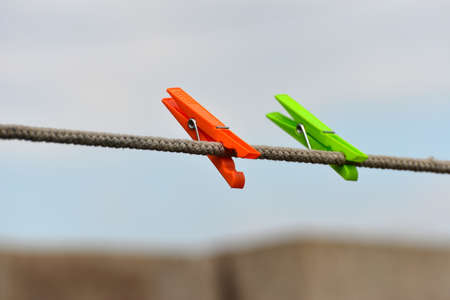 Multicolored plastic clothespins hang on the clothesline of the house.の写真素材