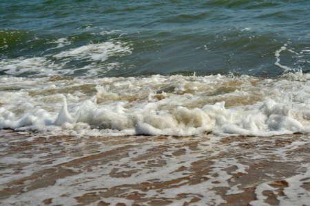Coast of the sea with stormy waves and sand. The concept of summer holidays during the holidays.