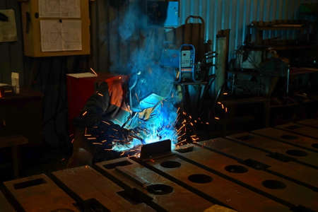Welder at work when processing metal in production. Sparks in the welding of steel.