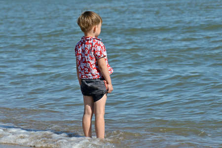 A boy on the beach went into the water and lookedの写真素材