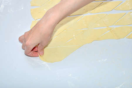 A raw dish of dough on a table, a woman making buns and patties and various figures in the kitchen for frying and eatingの写真素材