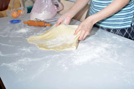 A raw dish of dough on a table, a woman making buns and patties and various figures in the kitchen for frying and eatingの写真素材