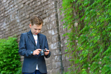A boy with a camera on the street looks at the photo, after the picture.の写真素材