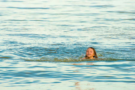 A girl floats in the sea on the ocean on a summer day.の写真素材