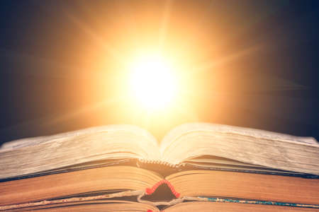 The open book lies on the table and the sun shines from it. Library, the concept of education. Empty place for text.の写真素材