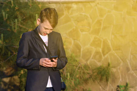 A boy with a smartphone reads a message in a smartphoneの写真素材
